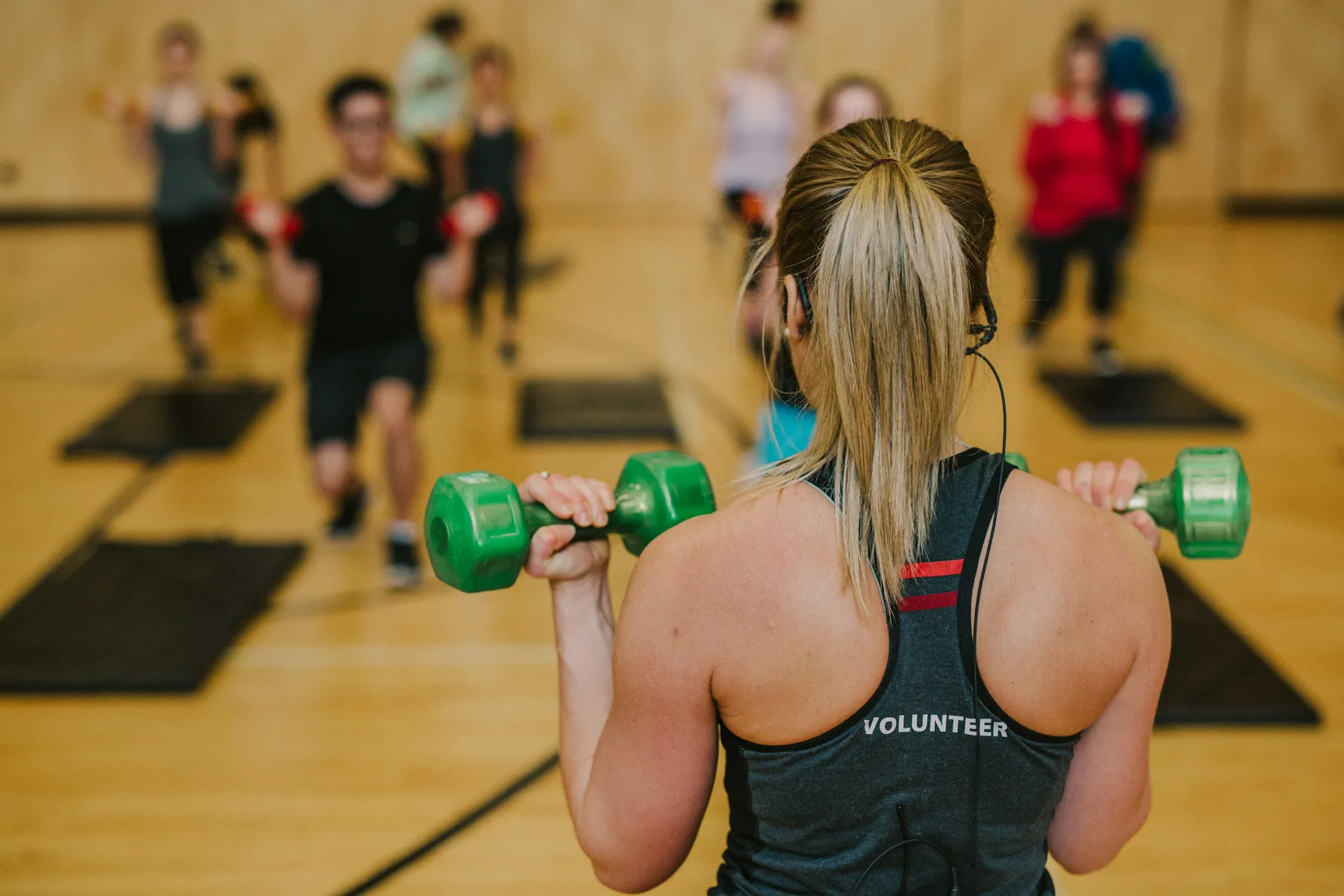 A volunteer YMCA fitness instructor leads a group class working out with dumbbells