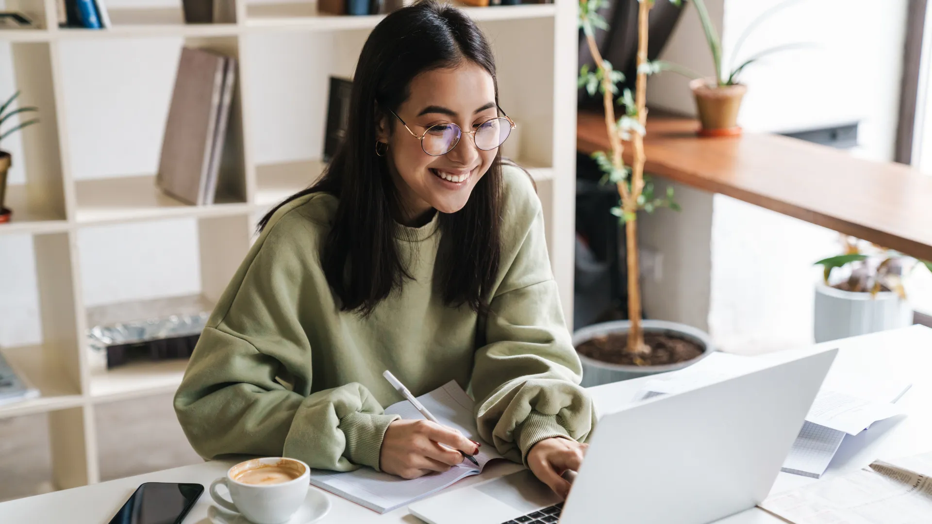 A young woman sits at a laptop to participate in a virtual job interview