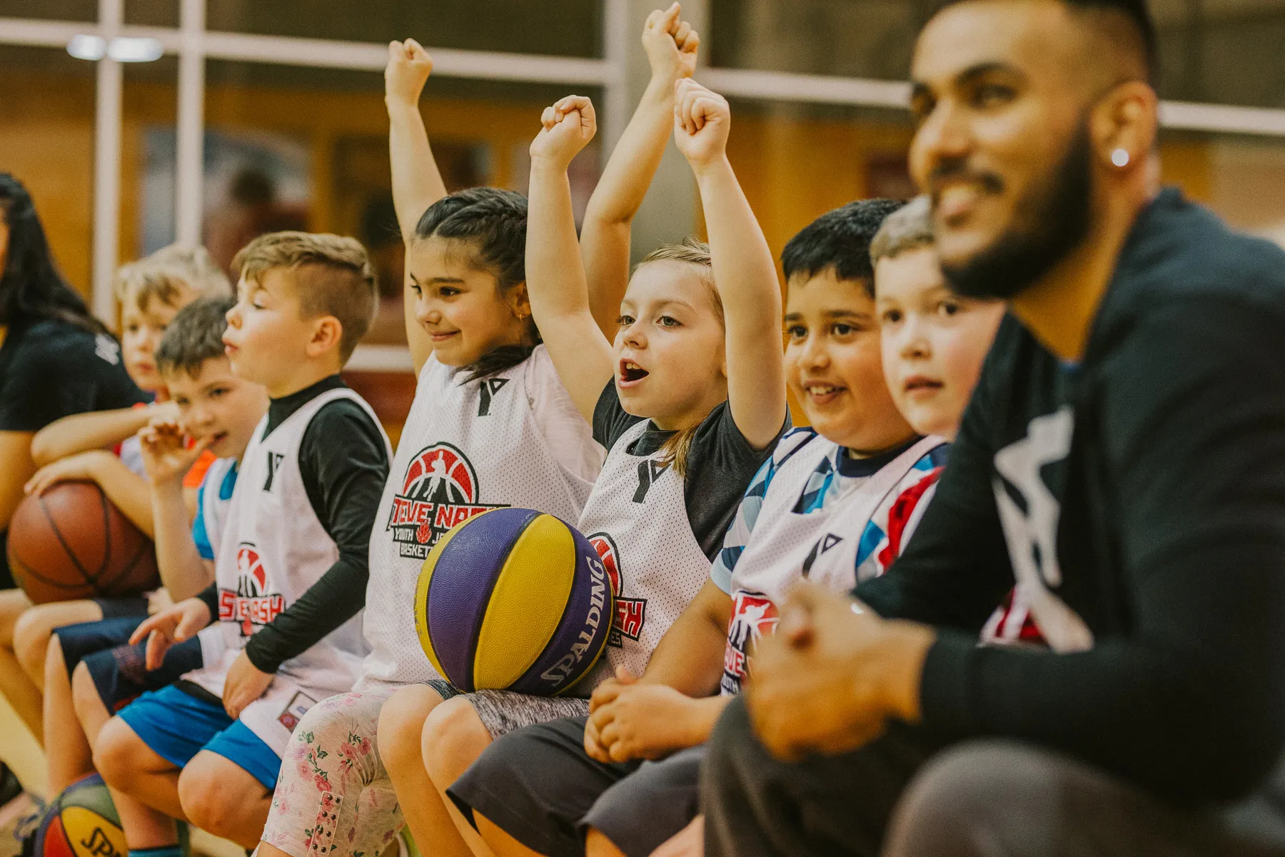 A basketball team of young boys and girls celebrates on their bench