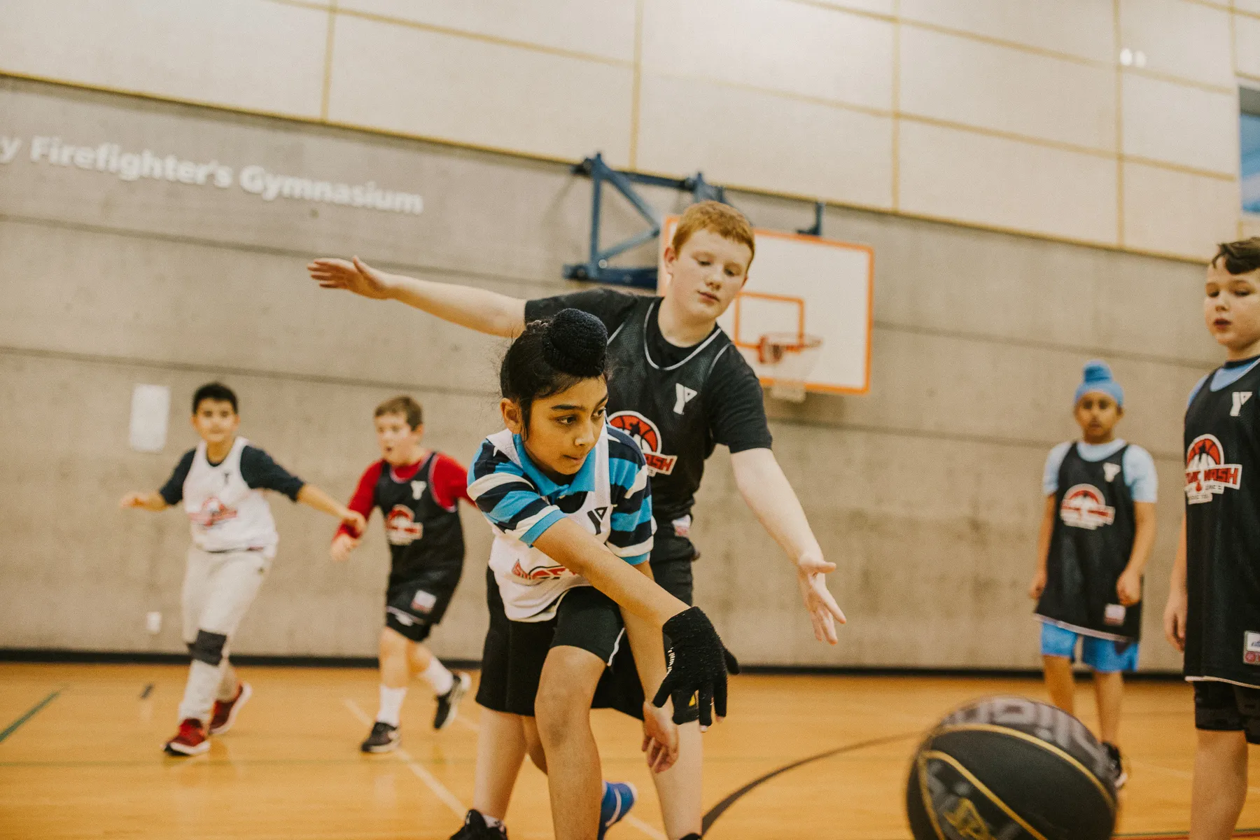 A youth basketball player makes a bounce-pass while being guarded by an opponent