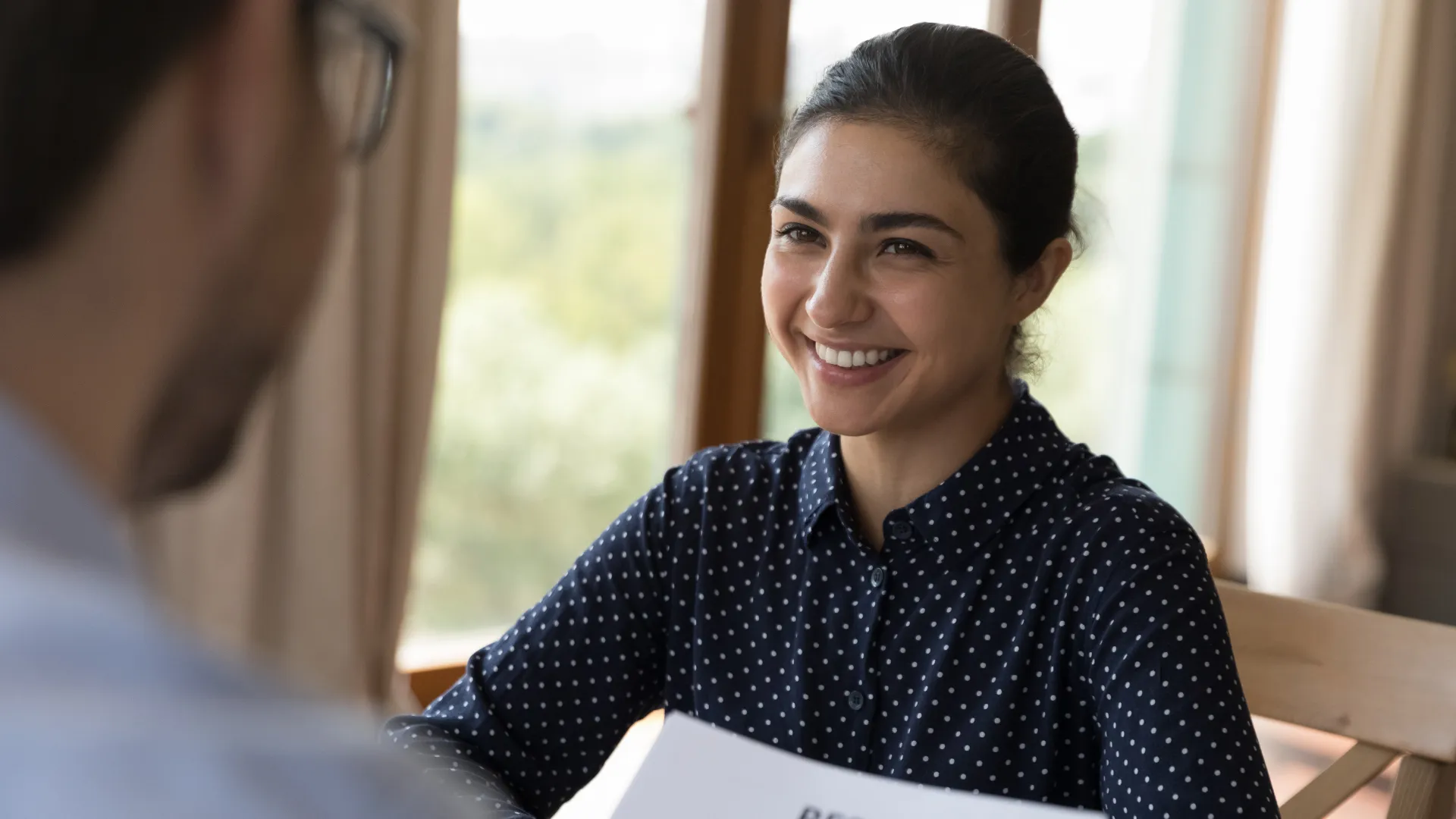 A smiling young woman participates in an in-person job interview
