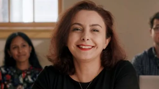 A close-up on a smiling woman who is sitting in a classroom