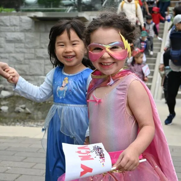 A young girl dressed as a Disney princess and another dressed as a superhero smile while participating in the YMCA Kids Walk for Community
