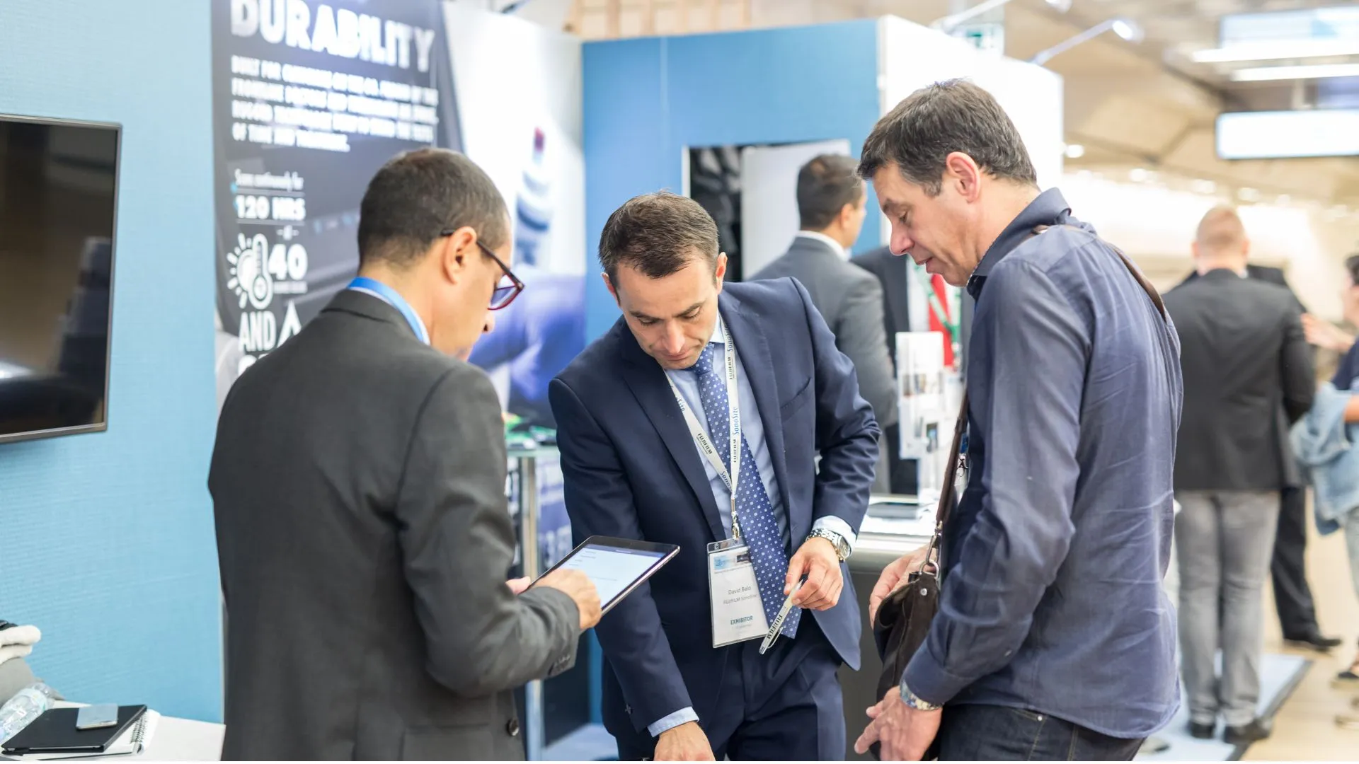 Three men have a conversation at a business expo