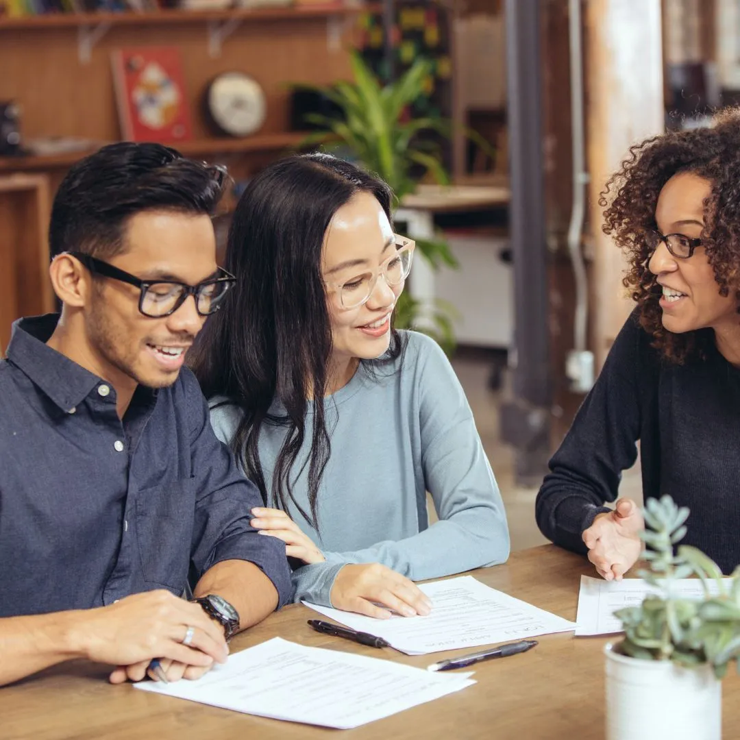 A young couple looks at papers in front of them while consulting with a financial advisor