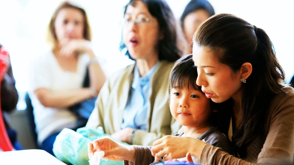 Woman holding her son on her lap in a busy room