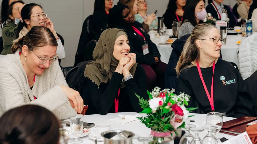 Three professionals from the child care sector smile while listening in at a YMCA CCRR professional development event