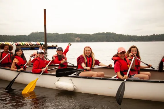 Camp counsellor and youth campers in a canoe on the water