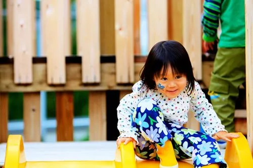 Young girl getting ready to go down playground slide