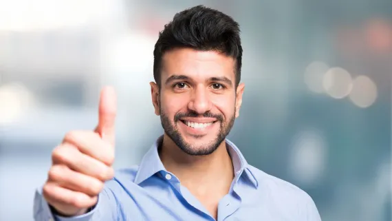 A smiling man giving a thumbs up