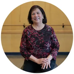 A YMCA Healthy Heart program participant smiling and sitting on a medicine ball