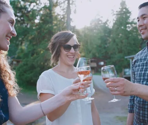 A group of people clink wine glasses to do cheers at YMCA Camp Elphinstone