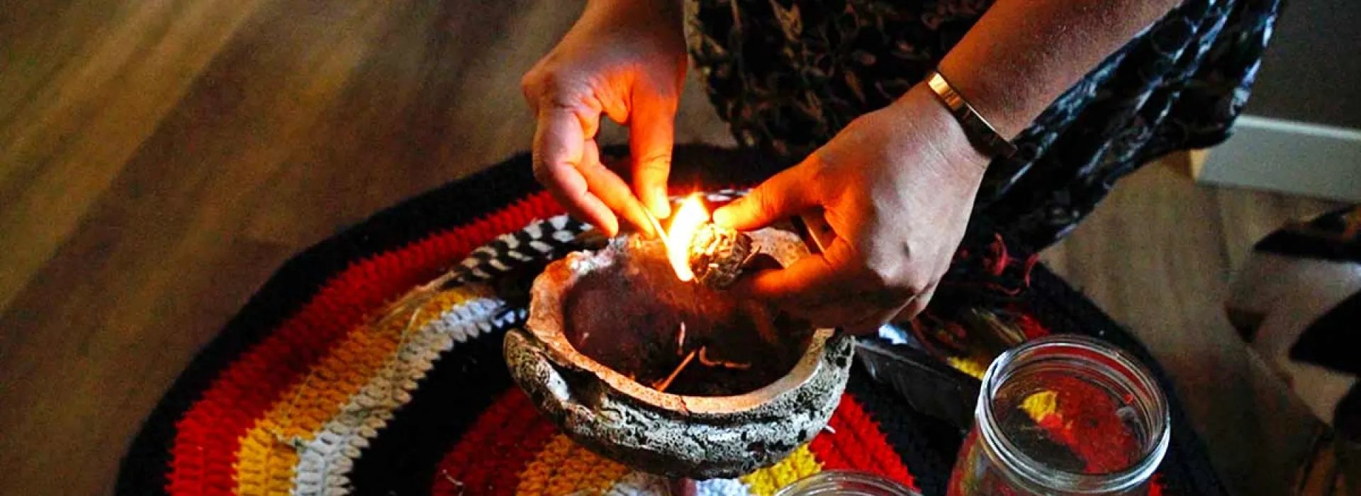 A Mind Medicine facilitator lights some wood over a bowl, incorporating an Indigenous custom into the program.